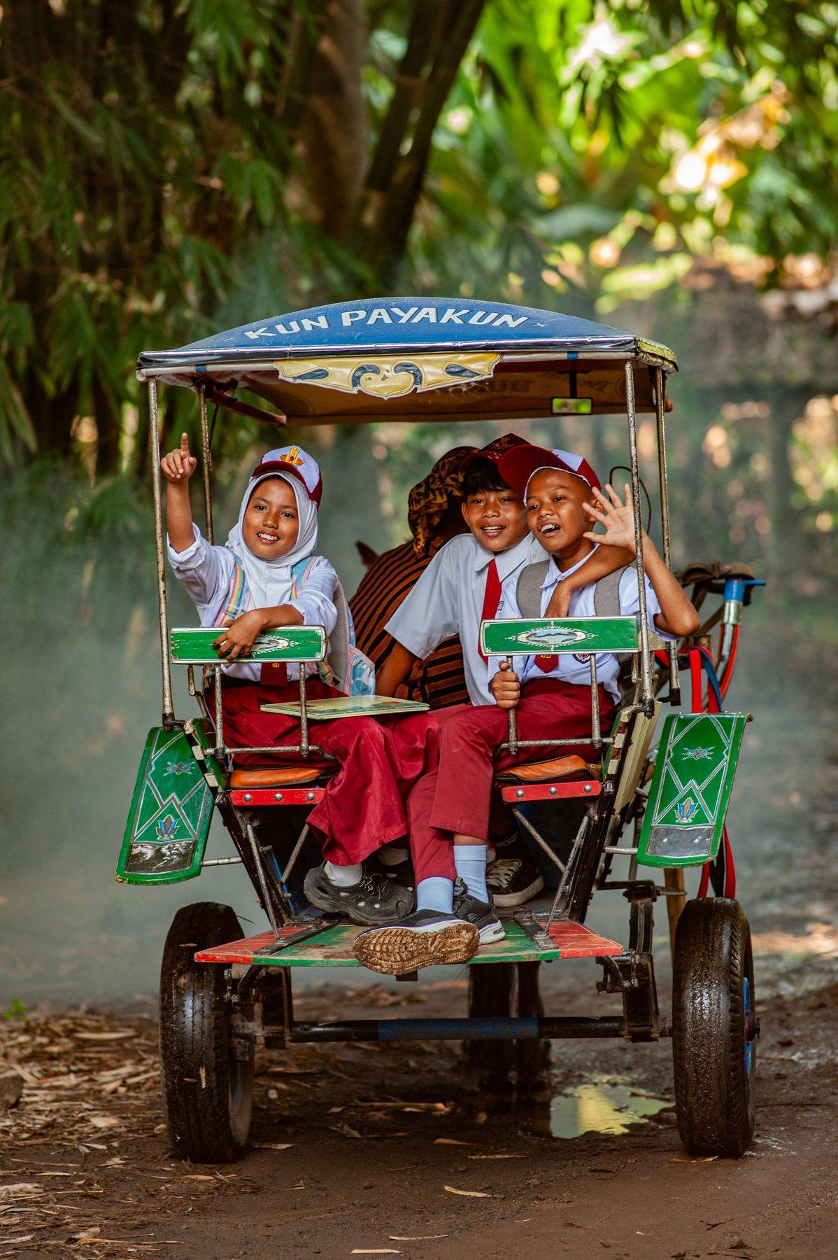 Siswa SD berseragam putih-merah tertawa di atas becak