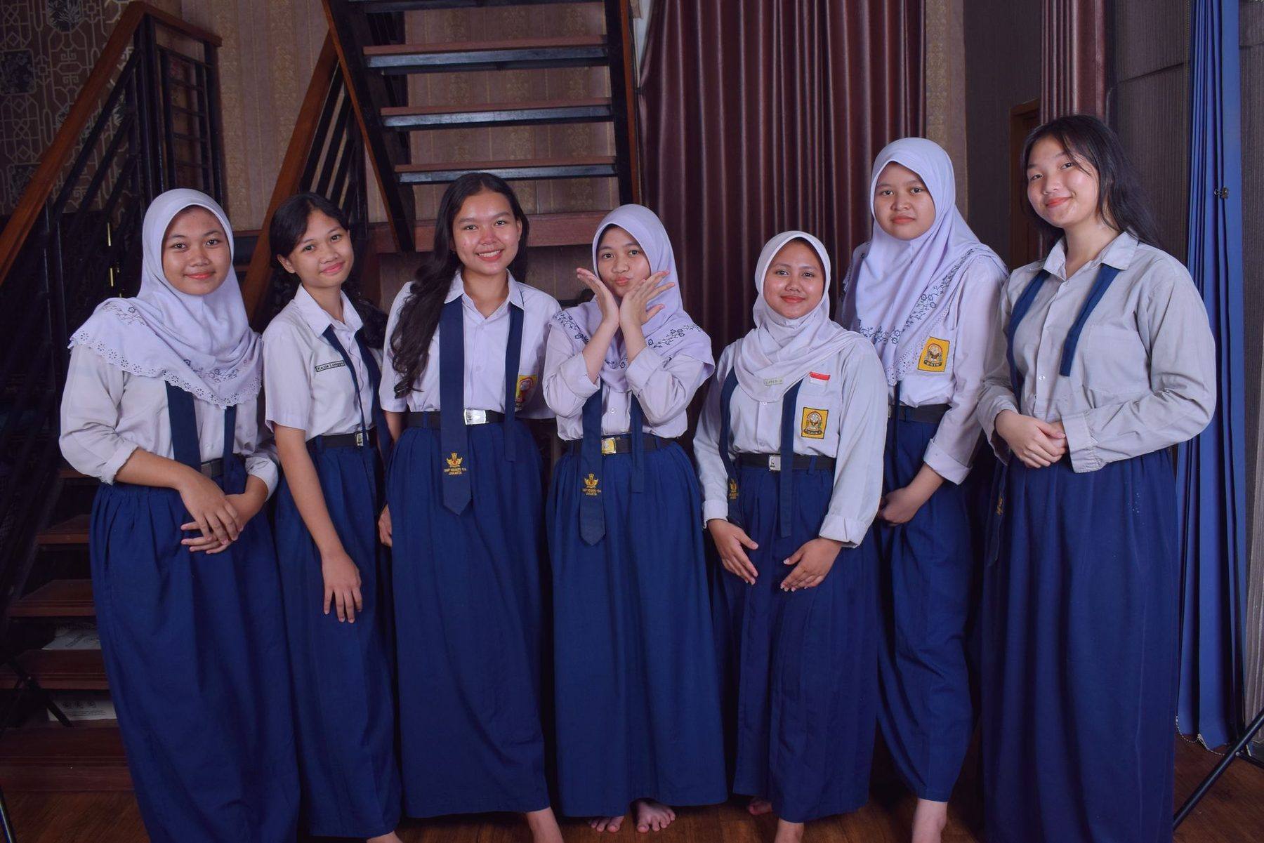 Siswi berseragam putih-biru berdiri bersama di dalam ruangan